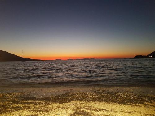 um pôr do sol sobre um corpo de água com uma praia em Sunset em Plataria