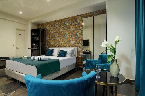 ein Hotelzimmer mit einem Bett und zwei blauen Stühlen in der Unterkunft Athens Imperial Suites - Luxury Living in Athen