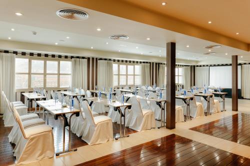 a dining room with tables and white chairs at Abba Euskalduna Hotel in Bilbao