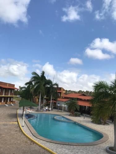 a swimming pool in a resort with palm trees at Chalé Temporada Porto dos Lençóis - Lençóis Maranhenses in Barreirinhas