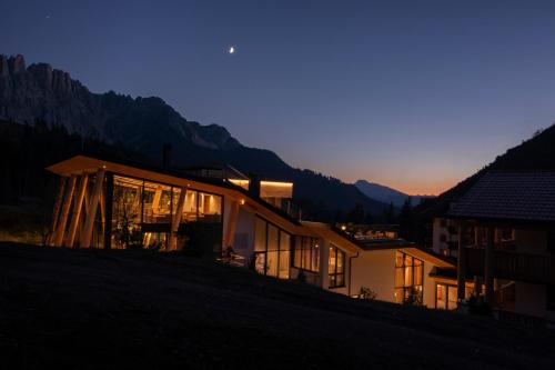 a house sitting on top of a hill at night at Moseralm Dolomiti Spa Resort in Nova Levante