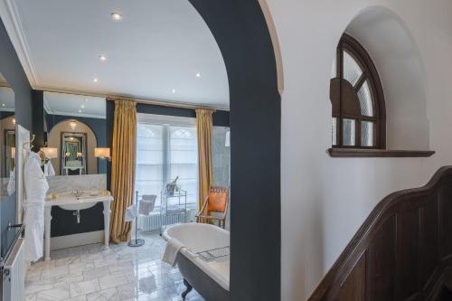 a bathroom with a tub and a sink in a room at Rushton Hall Hotel and Spa in Kettering