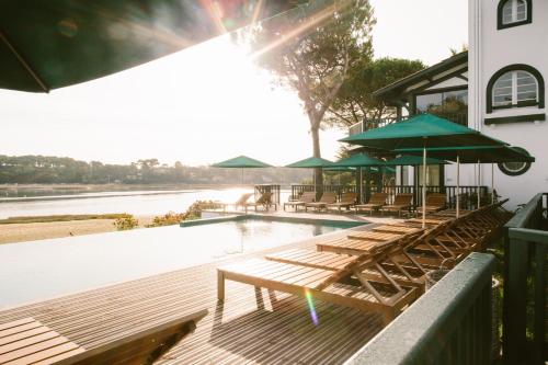 a pool with chairs and umbrellas on a deck at Hôtel Les Hortensias du Lac in Hossegor