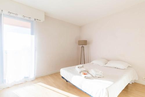 een witte slaapkamer met een bed en een raam bij Michel-Ange, Appartement avec Terrasse et Parking in Marseille
