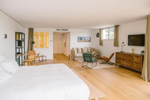 a bedroom with a white bed and a living room at Hôtel Les Hortensias du Lac in Hossegor