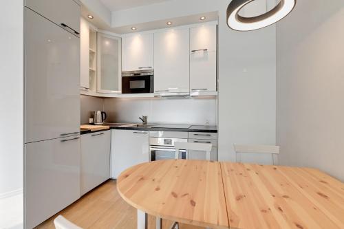 a kitchen with a wooden table and white cabinets at Holiday Apartment near the Sea - free private parking in Gdańsk