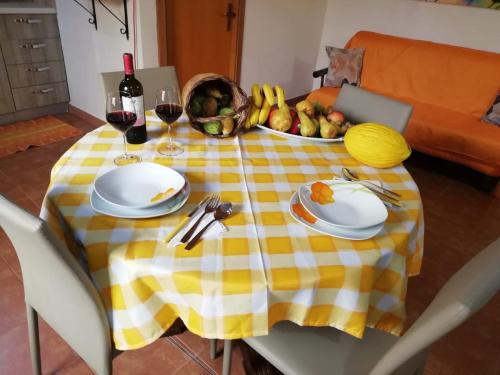 a yellow and white table with a bowl of fruit and wine glasses at La casa di Anita nel cuore di Segesta in Calatafimi