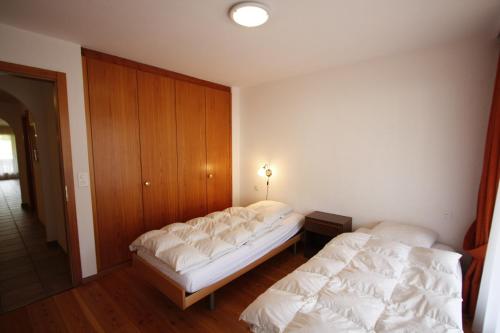 two beds in a room with white sheets at Apartment International in Crans-Montana