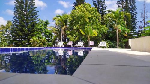 a swimming pool with chairs and trees in the background at CHÁCARA SANTA TERESA in Triunfo