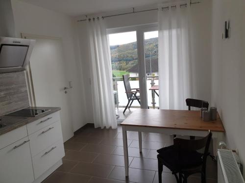 a kitchen with a table and a view of a balcony at FeWo Louise in Kinderbeuern