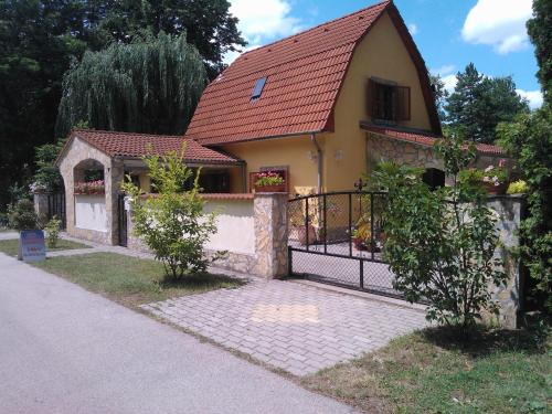 a small yellow house with a fence in front of it at Mediterrán Apartmanház Szántód in Szántód