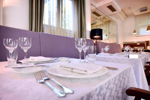 una mesa con mantel blanco y copas de vino en Hotel Ziya en Podgorica