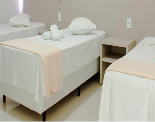 two beds with white sheets and pillows in a room at Hotel Recreio São Jorge in Jaboticabal