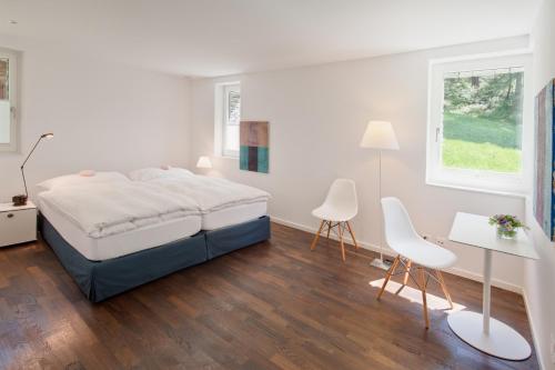 a white bedroom with a bed and a table and chairs at Chalet Altesse - Premium Apartments in Zermatt