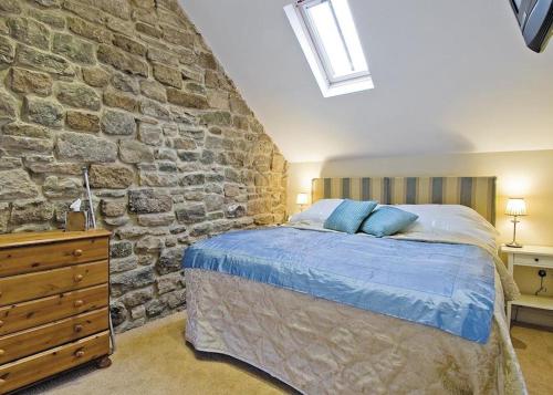 a bedroom with a stone wall and a bed at Riding Farm Cottages in Gateshead