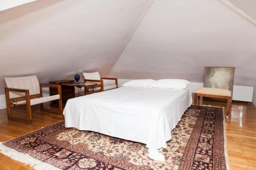 ein Schlafzimmer mit einem weißen Bett sowie einem Tisch und Stühlen in der Unterkunft Apollon Stone Villa in Delphi with Stunning View! in Delphi