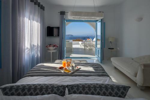 Un dormitorio con una cama con una bandeja de comida. en Kalestesia Suites en Akrotiri