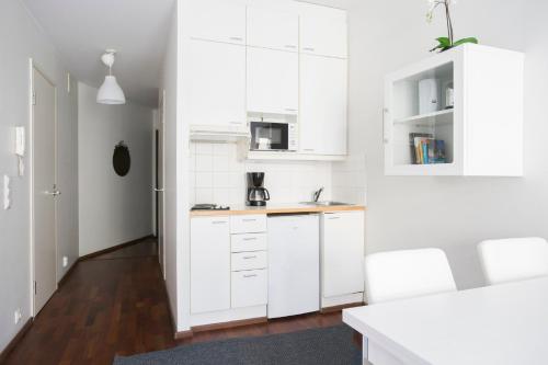 cocina blanca con armarios blancos y suelo de madera en 2ndhomes Kluuvi Studios, en Helsinki