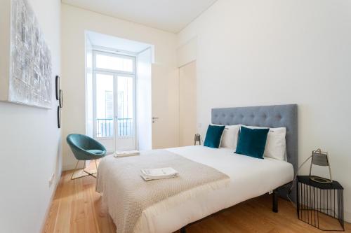 een witte slaapkamer met een groot bed met blauwe kussens bij FLH Chiado Modern Apartment in Lissabon