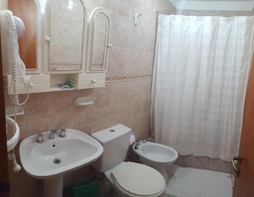 La salle de bains est pourvue de toilettes blanches et d'un lavabo. dans l'établissement Complejo El Puente, à Puerto Madryn