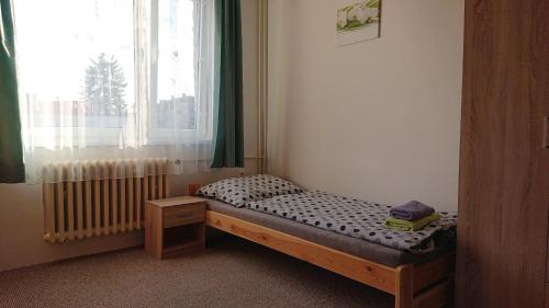 małe łóżko w pokoju z oknem w obiekcie Privát 347 w mieście Broumov