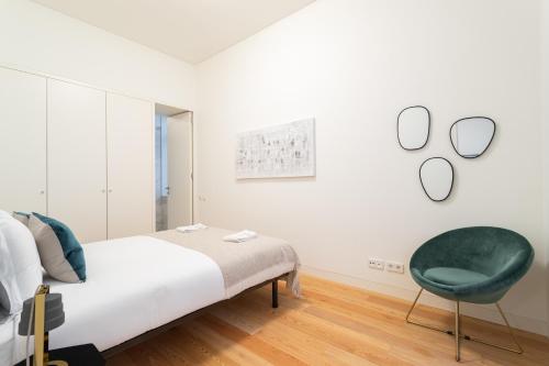 um quarto com uma cama e uma cadeira verde em FLH Chiado Trendy Apartment em Lisboa