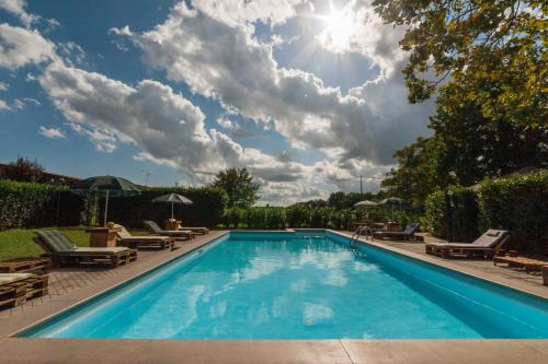 a swimming pool with chairs and the sun in the sky at Agriturismo Podernuovo in Acquapendente
