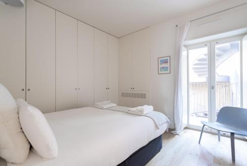 a white bedroom with a white bed and a blue chair at FLH Bairro Alto Modern Flats in Lisbon