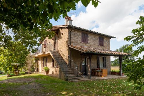 una vecchia casa in pietra con una scala che la porta di Agriturismo Podernuovo ad Acquapendente