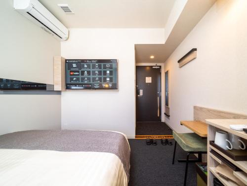 una camera d'albergo con letto, scrivania e finestra di Super Hotel Premier Akihabara a Tokyo