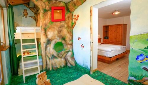 a bedroom with a tree mural on the wall at MyTime Hotels la Grotta in Vigo di Fassa