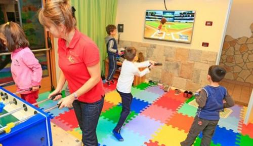 a woman and children playing a game in a room at MyTime Hotels la Grotta in Vigo di Fassa