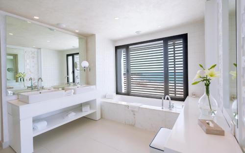 a bathroom with two sinks and a tub and a large window at La Badira - Adult Only in Hammamet