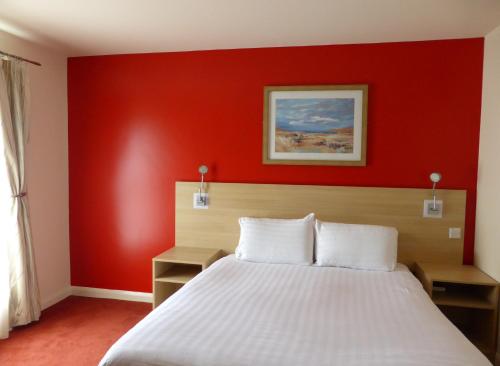 um quarto com uma parede vermelha e uma cama em The Welcome Inn Rotherham/Sheffield em Rotherham