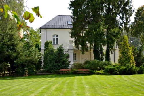 a large white house with a lawn and trees at Dwór w Zabużu in Zabuże