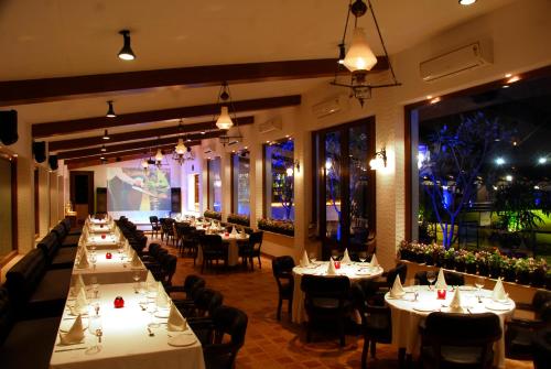a restaurant with white tables and chairs and lights at Della Resorts in Lonavala