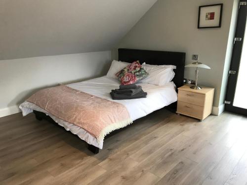 a bedroom with a bed with white sheets and a wooden floor at Lakeside Studio 1 Loft Apartment in Enniskillen
