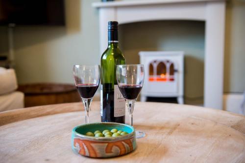 a bottle of wine and two wine glasses on a table at Gwalia House- Stunning Central Townhouse with 3 ensuite bedrooms in Laugharne