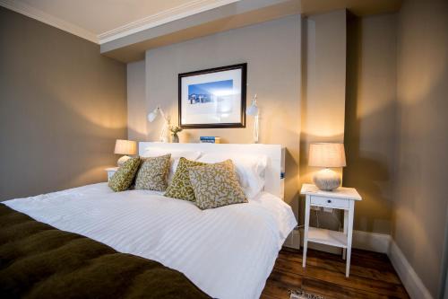 a bedroom with a large white bed with pillows at Gwalia House- Stunning Central Townhouse with 3 ensuite bedrooms in Laugharne