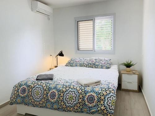 a white bedroom with a bed and a window at Mor's Place in Beer Sheva