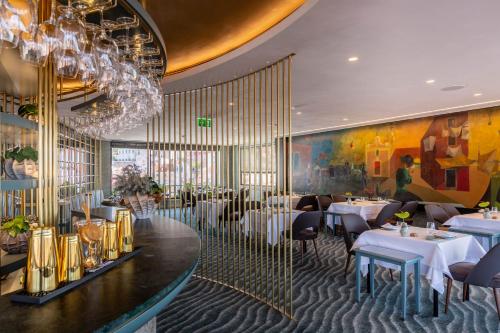 ein Restaurant mit Tischen, Stühlen und einem Kronleuchter in der Unterkunft Hotel Mundial in Lissabon