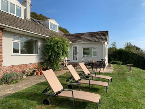 a group of chairs sitting on a lawn in front of a house at Nettle Bank in Lyme Regis