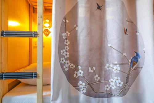 重慶市にある弱水咖啡国际青旅 Only Cafe and Backpackerの鳥と花のカーテン付きベッド