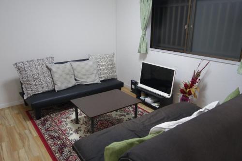 a living room with a couch and a tv at Taro's House Kamakura Hase in Kamakura