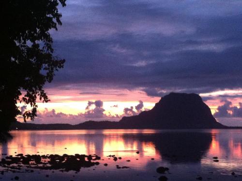 a sunset over a body of water with a mountain at Otium in Coteau Raffin