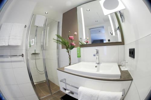 ein Bad mit einem Waschbecken, einer Dusche und einem Spiegel in der Unterkunft Boutiquehotel am Stadtgarten in Freiburg im Breisgau