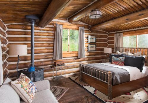ビッグスカイにあるLone Mountain Ranchのベッドルーム1室(ベッド1台付)、暖炉が備わるログキャビンです。