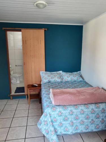- une chambre avec un lit et un mur bleu dans l'établissement Casa caiçara, à Parati