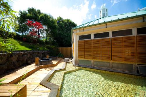 a garden with a house and a pond at Kijima Kogen Hotel in Beppu