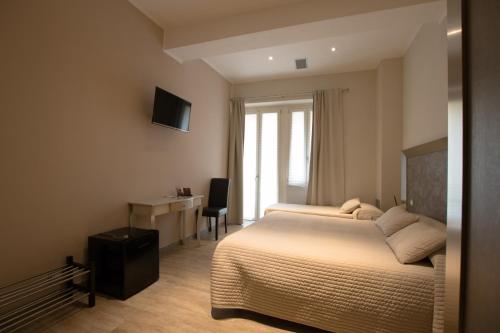 una camera con 2 letti, una scrivania e una TV di Residenza Solferino a Cremona